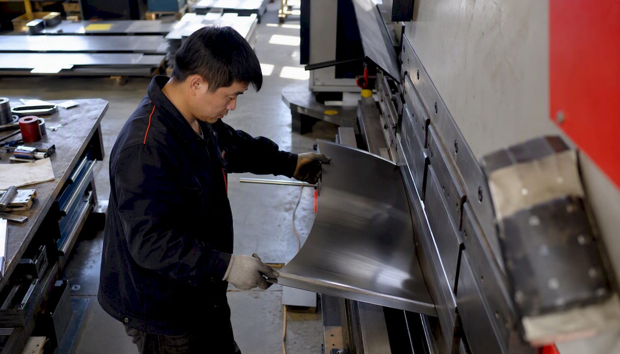 Worker bending sheet metal on press brake
