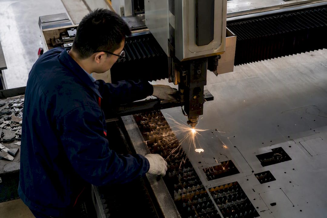 Engineer adjusting laser cutter on metal sheet
